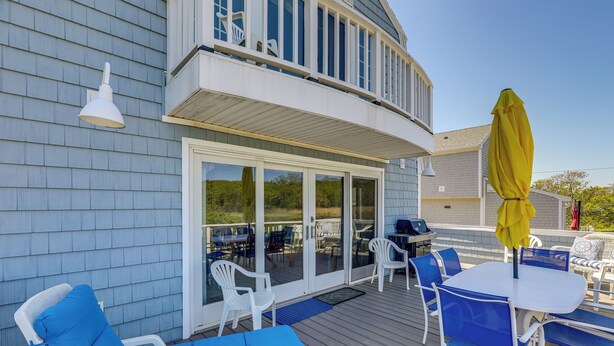 Une terrasse extérieure couverte, avec une table et des chaises, un parasol jaune et une chaise placée au bord de la piscine.