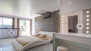 A modern bedroom with a curved bed, a vanity with a mirror and lights, and a patterned wall. - Beautiful home in Marbella (Marbella)