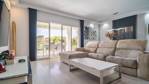 A modern living room with a beige sectional sofa, a glass coffee table, and a dining area with a table and chairs. - Beautiful home in Marbella (Marbella)