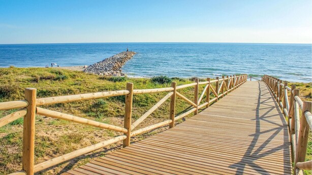 A wooden boardwalk leading to a rocky shoreline with a clear view of the ocean. - Beautiful home in Marbella (Marbella)