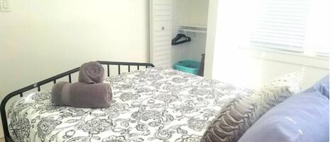 A bedroom with a bed, a pillow, a rolled towel, and three wall art pieces.