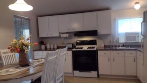 Une cuisine moderne avec des meubles blancs, une cuisinière et un coin repas comprenant une table et des chaises.