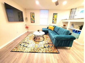 A living room with a teal sofa, a round coffee table, and a patterned rug. - Centrally Located Beachy Boho 3 bdr KING (St. Petersburg)