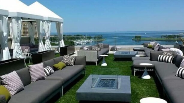 Un salon sur le toit offrant une vue sur la mer, avec des canapés, un foyer et un espace aménagé sous une tente.