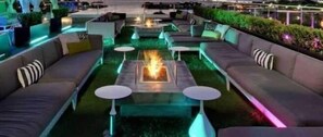 Un espace de détente moderne, doté de canapés, de tables et d’un foyer central.