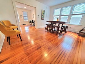 Relax in this serene space with a dining area, comfortable armchair, and natural light pouring in through the window.
