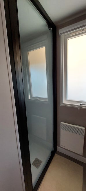 Een kamer met een schuifdeur van glas, een raam met jaloezieën en een radiator aan de muur.