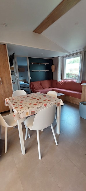 Een eetgedeelte met een tafel en stoelen, een bank en een raam met gordijnen.
