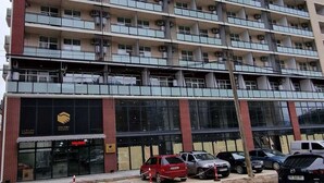A multi-story building with a series of balconies and a ground-level commercial space with a visible sign. - Salami Residence (Batumi)