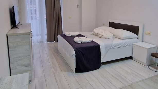 A modern hotel room with a bed, bedside table, and a desk with a chair. - Salami Residence (Batumi)