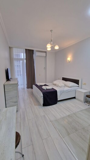 A modern hotel room with a bed, bedside table, and a desk with a chair. - Salami Residence (Batumi)