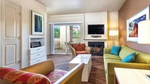 A hotel room with a living area featuring a sofa, armchairs, a coffee table, a flat-screen TV, a fireplace, and a balcony with outdoor seating. - 1BD Las Vegas Boulevard w/Lazy river, Shuttle and near the Strip! (Las Vegas)