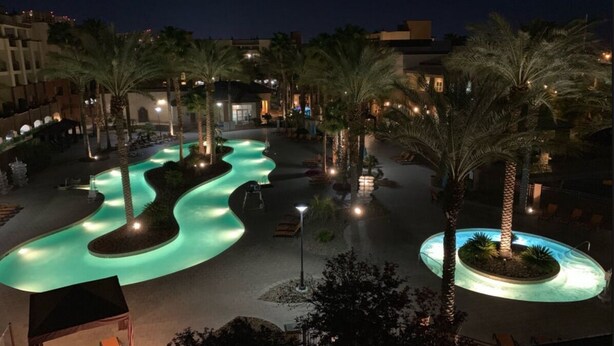 A nighttime view of a resort with a winding pool, palm trees, and outdoor seating areas. - 1BD Las Vegas Boulevard w/Lazy river, Shuttle and near the Strip! (Las Vegas)