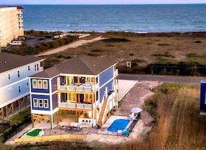 Um imóvel à beira-mar com vários andares, piscina, área de estar externa e vista para o oceano.