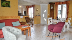 Un salon comprenant un canapé, un fauteuil à bascule et un coin repas avec une table et des chaises.
