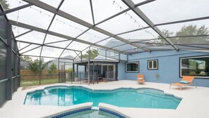 A covered swimming pool with a hot tub, lounge chairs, and a glass-enclosed patio area. - Mid-century Modern Villa w/ Pool Near Universal (Orlando)