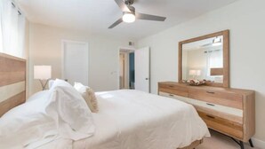 A bedroom with a bed, a dresser, a ceiling fan, and a mirror. - Mid-century Modern Villa w/ Pool Near Universal (Orlando)