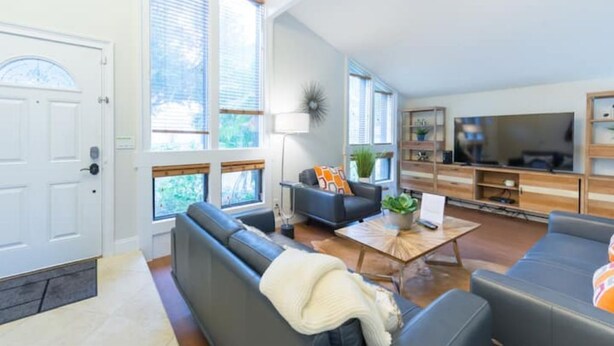 A spacious living room with a sofa, coffee table, and TV. - Mid-century Modern Villa w/ Pool Near Universal (Orlando)