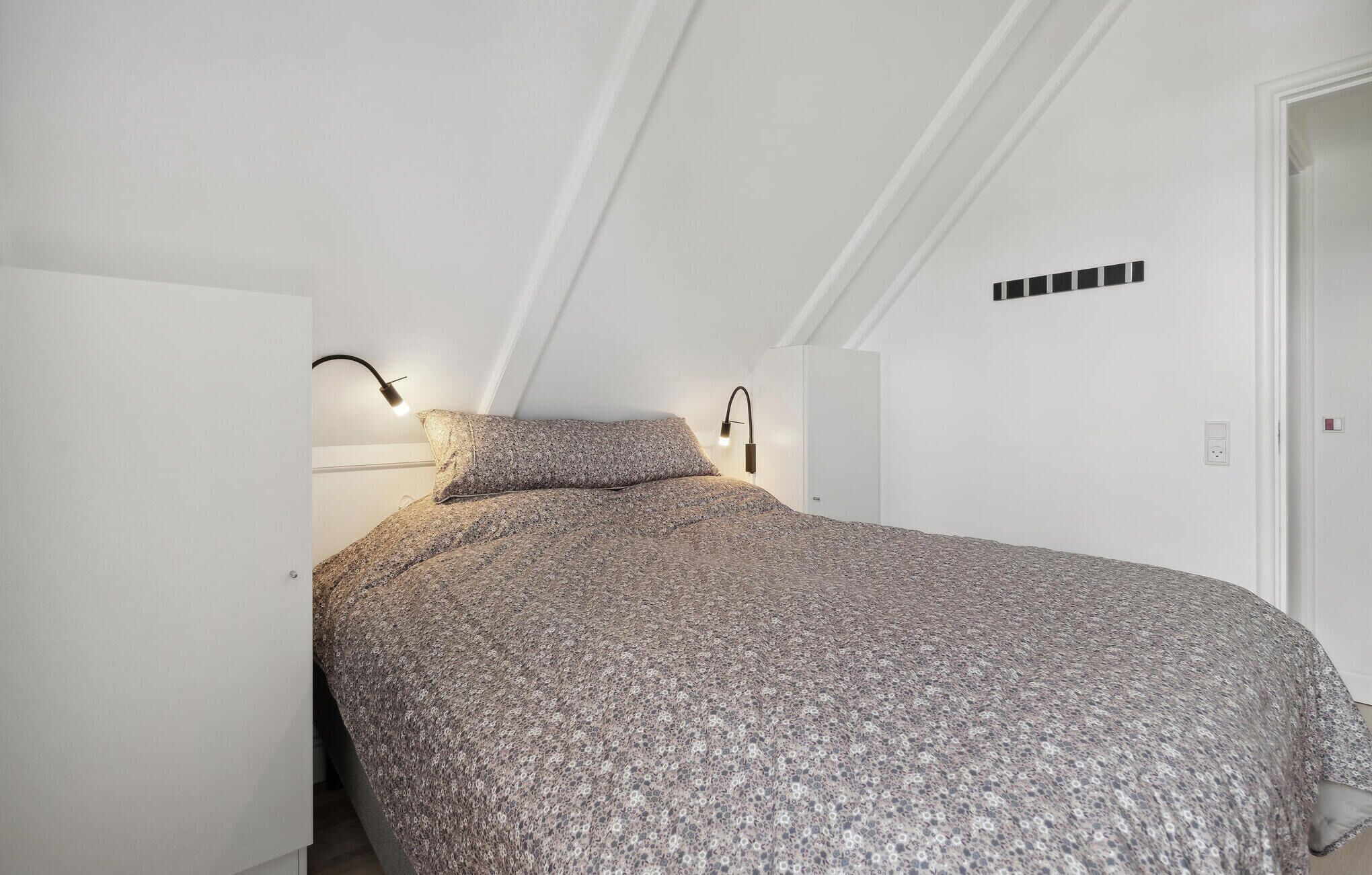 Ein Schlafzimmer mit einem Bett, zwei Wandlampen und einer Tür.