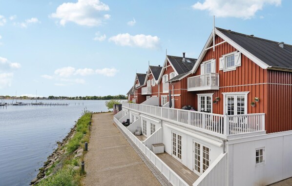 Traditional Scandinavian-style houses line the tranquil waterfront, featuring balconies and a wooden deck.