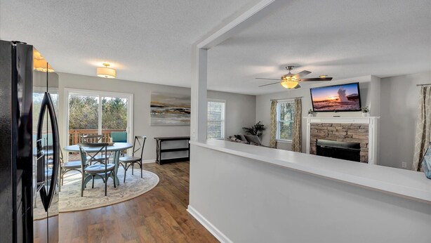 A modern kitchen with a built-in refrigerator, a dining area with a round table and chairs, a fireplace, and a television mounted above it.