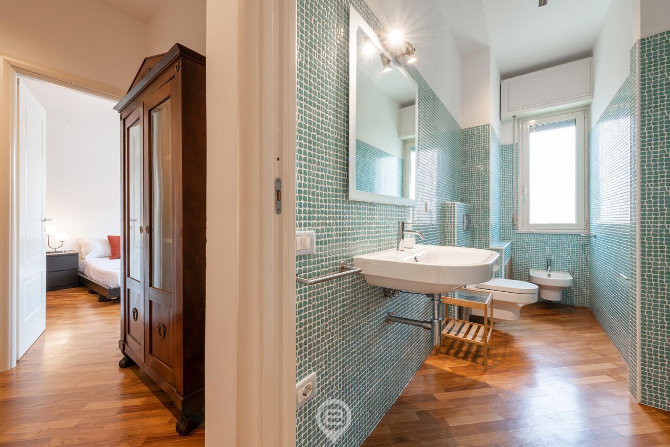 A bathroom with a large mirror, a sink, and a toilet.