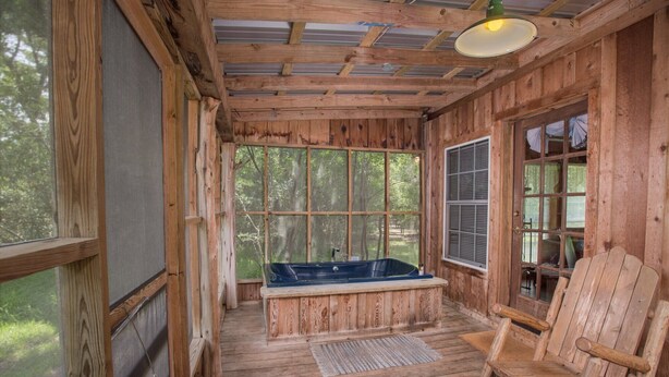 Un rifugio rustico con interni in legno, un'ampia finestra, una vasca da bagno e una sedia di legno.