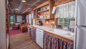 Una cucina rustica con mobili in legno, un lavello e un'area pranzo con tavolo e sedie.
