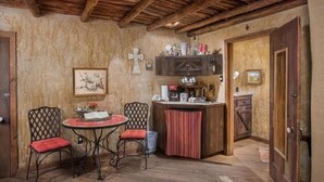 Een rustieke kamer met een houten plafond, een kleine eettafel met stoelen, een bar en een deur naar een andere ruimte.