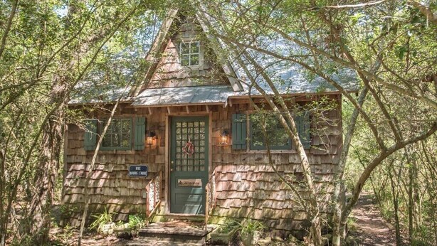 A rustic cabin with a steeply pitched roof, a green door, and a small porch.