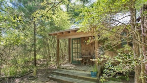 A rustic wooden cabin with a green door, a small porch, and a table and chairs.