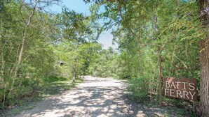A dirt path leading through a forested area with a sign reading "BATS FERRY". - 7F Lodge - Batts Ferry Cabin w/Breakfast - Log Cabin w/ Jacuzzi Tub and Fire Pit (College Station)