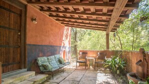 Eine überdachte Terrasse mit einer Holzbank, einem Tisch und Stühlen.