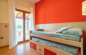 Une chambre avec un lit superposé, une porte-fenêtre coulissante donnant sur un espace extérieur et un mur rouge.