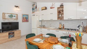 Een moderne keuken met witte kasten, een eettafel gedekt voor vier personen en een televisie in de hoek.