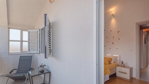 Een kamer met een bed, een stoel, een tafel en een raam met zonwering.