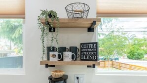 Una cocina con estación de café, que incluye cafetera, tazas y un letrero que dice 'Coffee and Friends a Perfect Blend'.