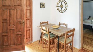 Una mesa de comedor de madera con cuatro sillas, un reloj decorativo en la pared y un cuadro enmarcado.
