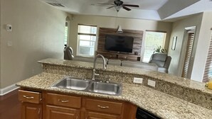 A kitchen with granite countertops, wooden cabinets, a dishwasher, and a ceiling fan. - Amazing and spacious home. 4be2Bth, and beautiful screened private pool. (Port St. Lucie)