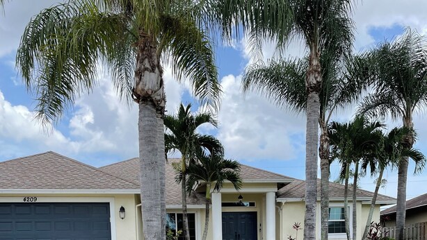 A residential house with a garage, palm trees, and a well-maintained lawn. - Amazing and spacious home. 4be2Bth, and beautiful screened private pool. (Port St. Lucie)
