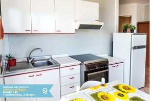 A compact kitchen with white cabinets, a sink, a stove, and a refrigerator.