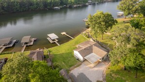 Una propiedad junto al lago con barcos amarrados, un área de césped y una casa con techo inclinado.
