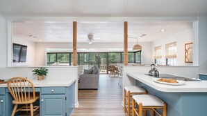 Una cocina amplia con una isla central, sillas de madera y vista a un balcón.