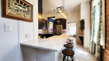 A modern kitchen with a marble countertop, black cabinets, and a hanging light fixture.
