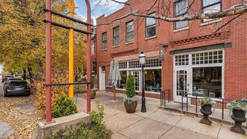 A brick building with a storefront, outdoor seating, and a decorative metal structure.