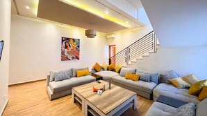 A modern living room with a sectional sofa, a wooden coffee table, and a staircase. - Riad villa saphir & SPA (Marrakech)
