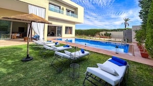 A modern two-story building with a swimming pool, outdoor seating, and a well-maintained lawn. - Riad villa saphir & SPA (Marrakech)