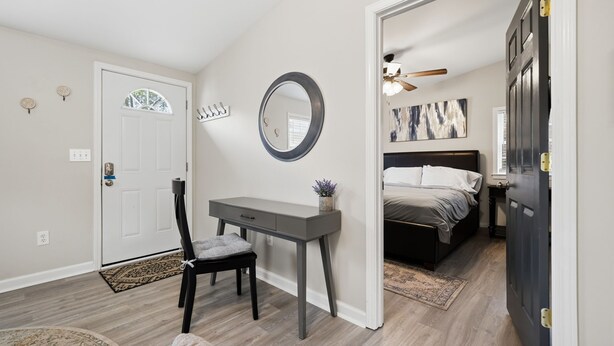 Un dormitorio con escritorio, silla, cama y una puerta que da a otra habitación.