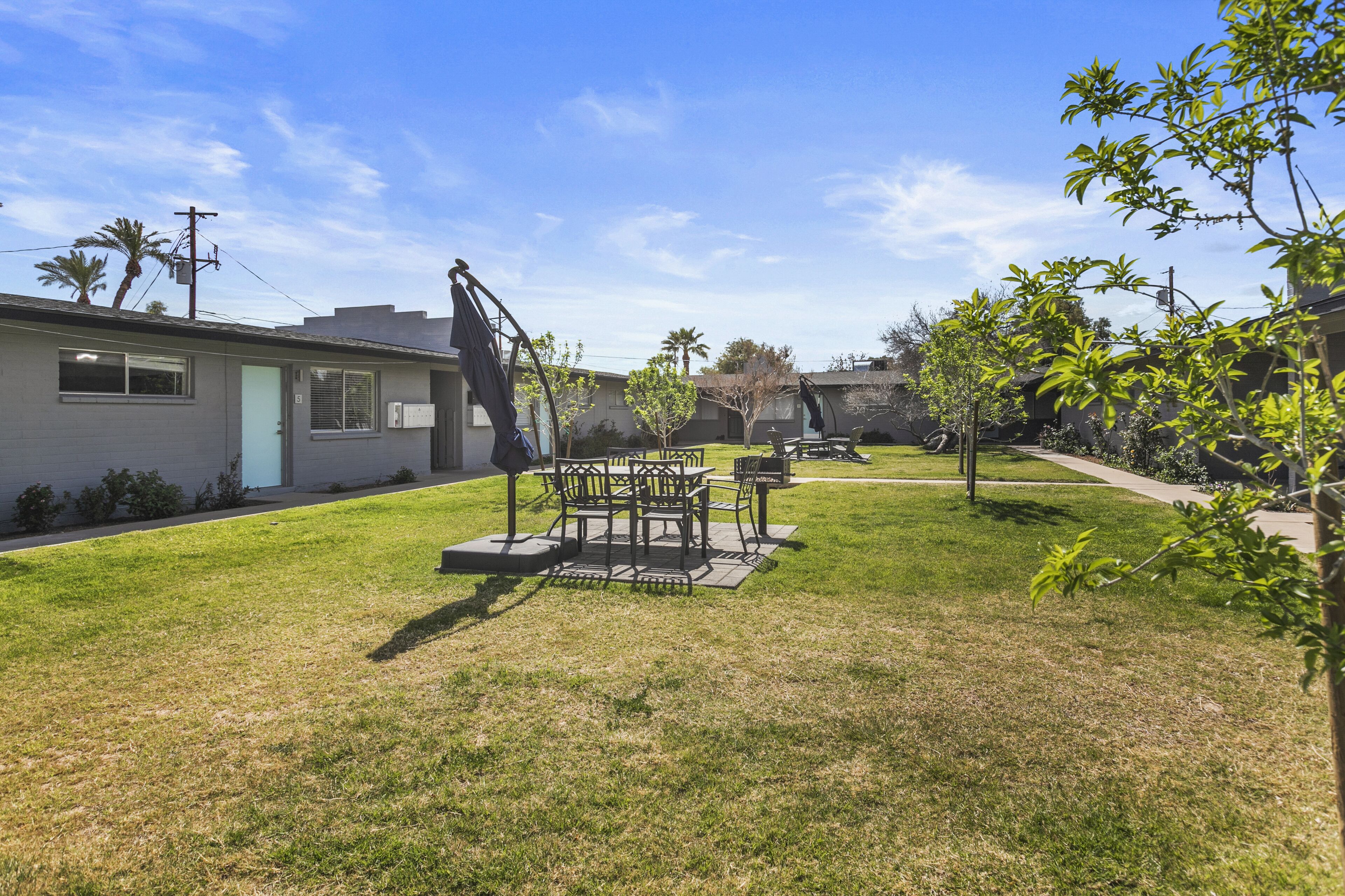 A backyard with a patio table and chairs, a small garden, and a house with a garage.