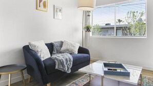 A modern living room with a dark blue sofa, a white coffee table, and a patterned rug. - Contemporary Condo in Central Biltmore (Phoenix)